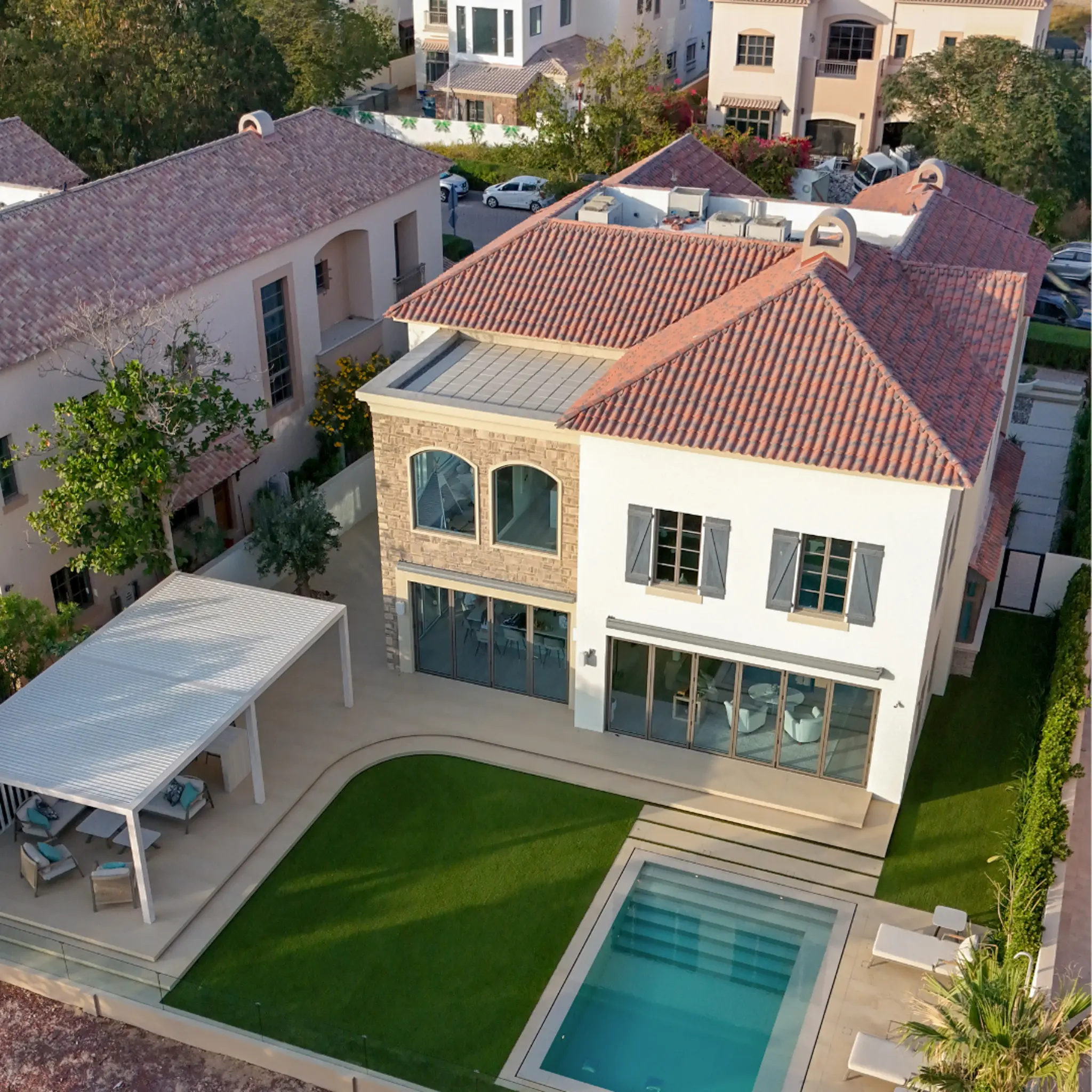 Landscape architecture and design service in Dubai, shown in an aerial view of a villa garden with a swimming pool, lawn, paved terraces and pergola