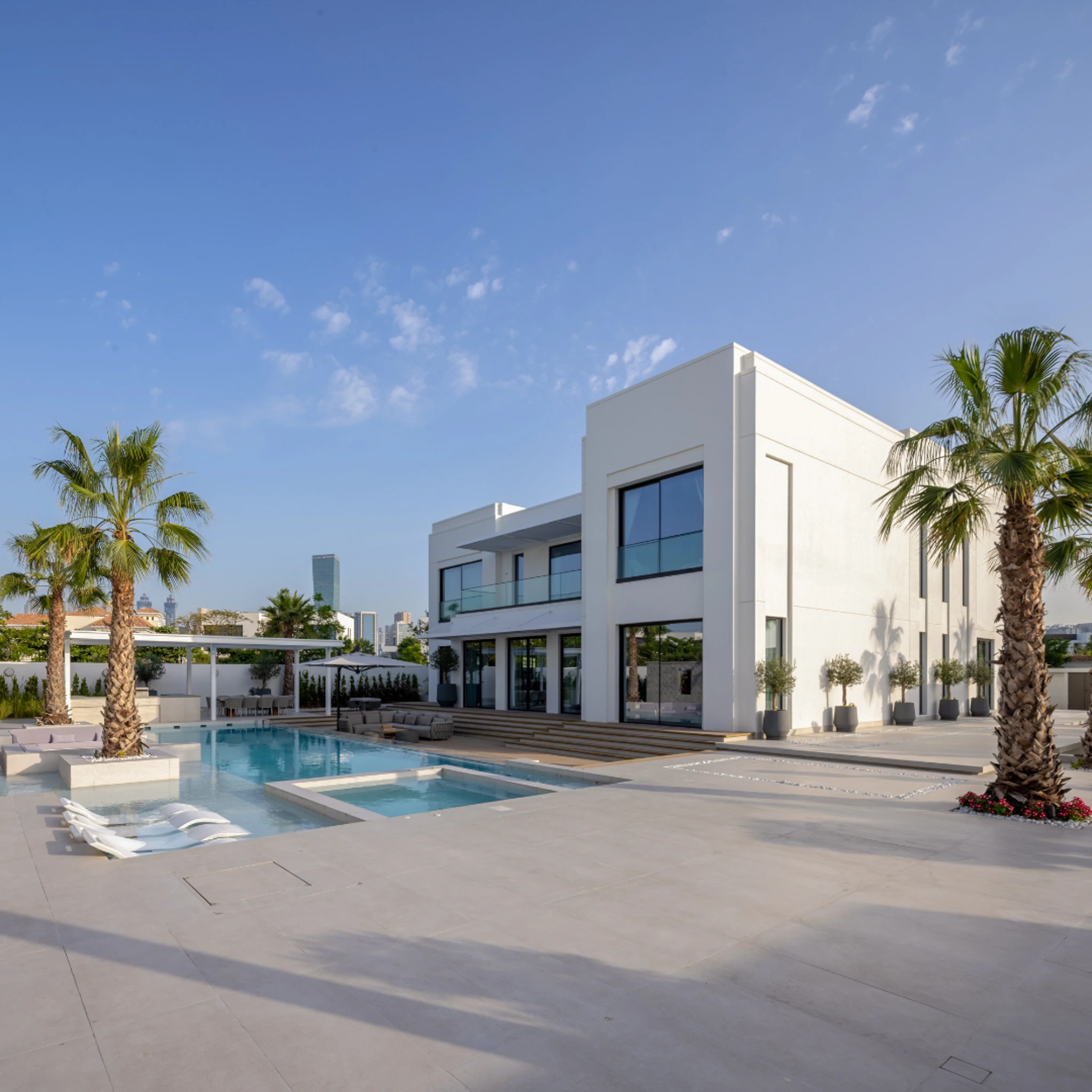 Swimming pool, water feature and outdoor living design service in Dubai, shown as a villa pool terrace with a sunken jacuzzi, in-water loungers and shaded dining pergola