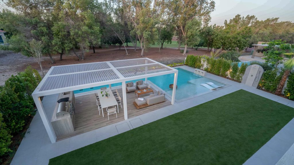 Villa landscape design and build in Dubai with a swimming pool, water spouts, in-water loungers, lawn and shaded pergola lounge