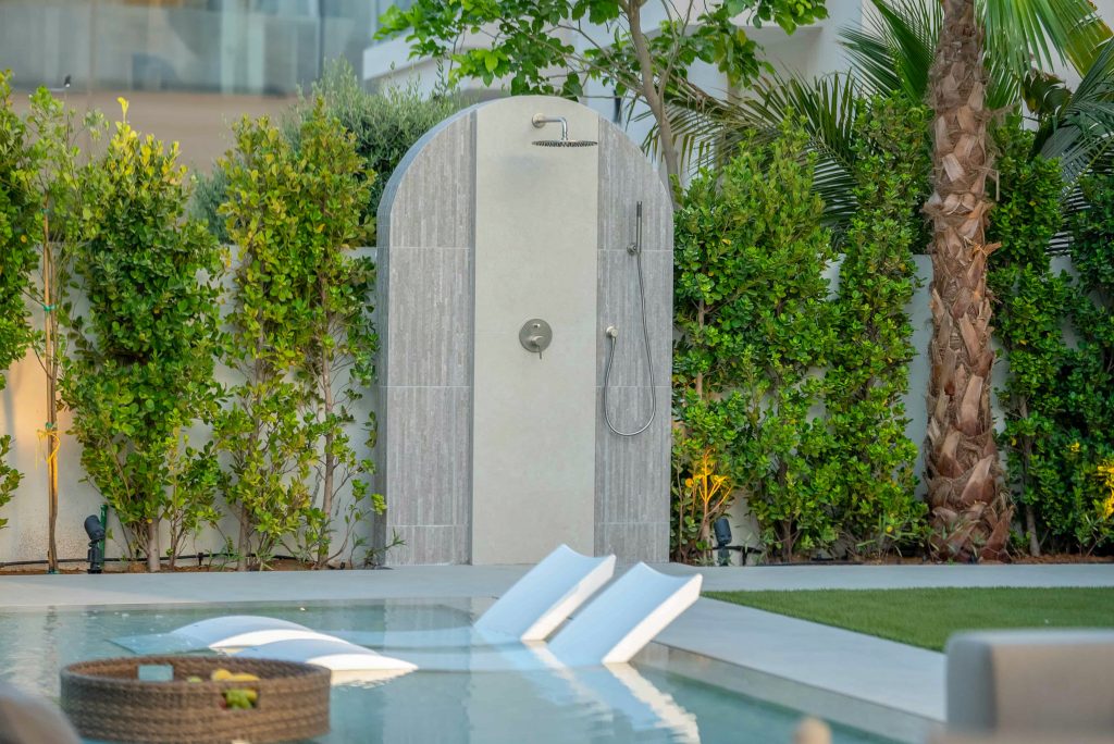 Villa landscape design and build in Dubai with a swimming pool, water spouts, in-water loungers, lawn and shaded pergola lounge