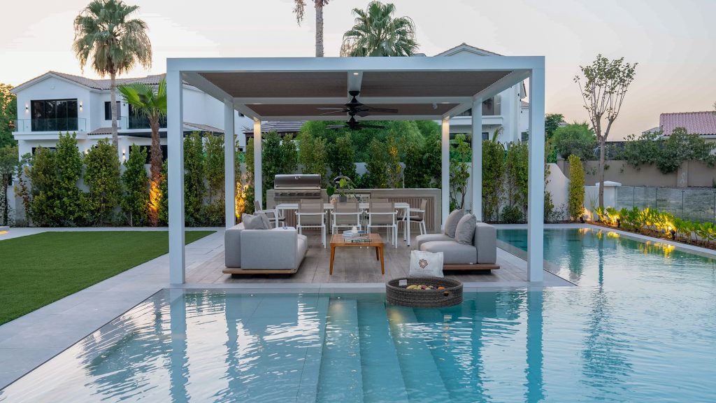Villa landscape design and build in Dubai with a swimming pool, water spouts, in-water loungers, lawn and shaded pergola lounge