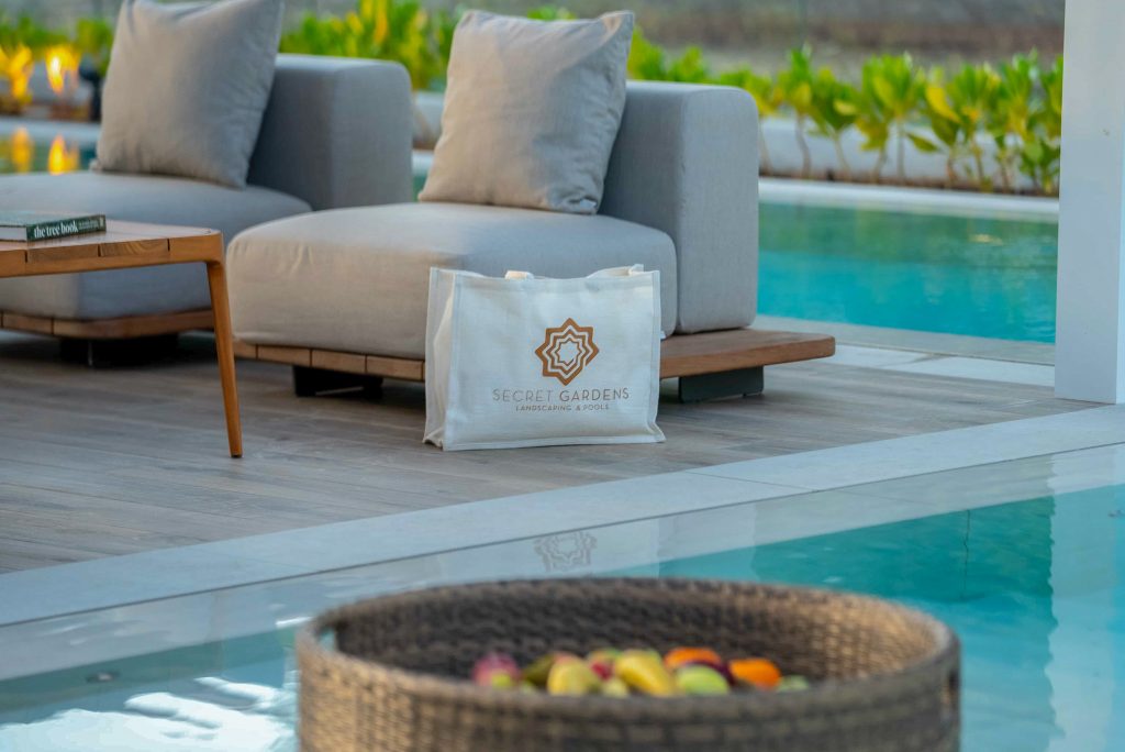 Villa landscape design and build in Dubai with a swimming pool, water spouts, in-water loungers, lawn and shaded pergola lounge
