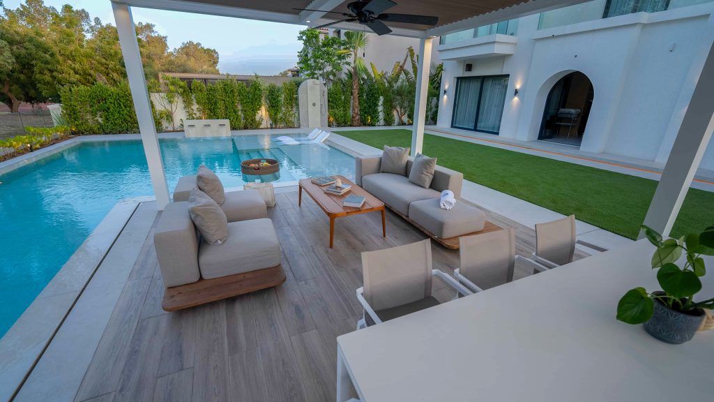 Villa landscape design and build in Dubai with a swimming pool, water spouts, in-water loungers, lawn and shaded pergola lounge