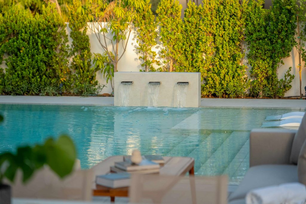 Villa landscape design and build in Dubai with a swimming pool, water spouts, in-water loungers, lawn and shaded pergola lounge