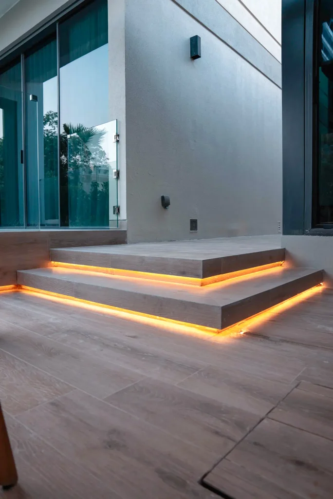 Landscape lighting design in Tilal Al Ghaf, Dubai with concealed LED strip lighting under timber-effect deck steps