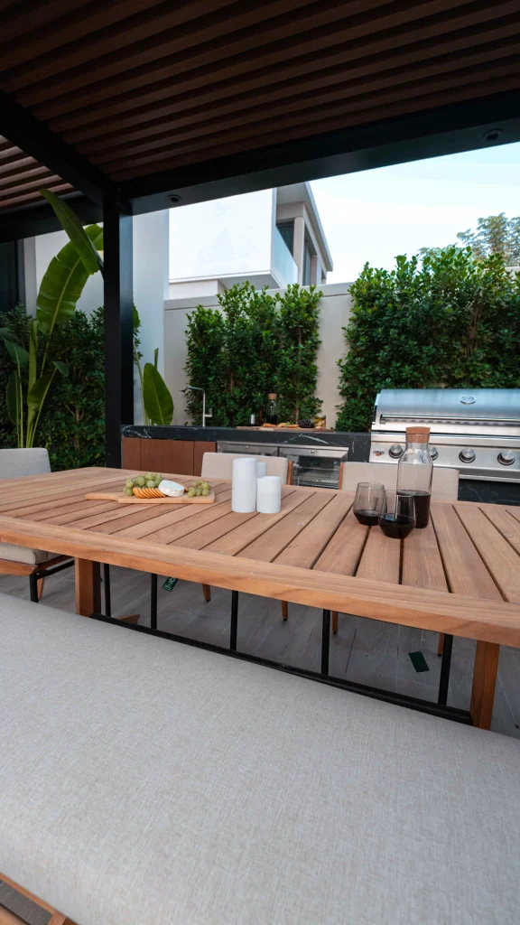 Outdoor dining and kitchen landscape design under a slatted pergola in Tilal Al Ghaf, Dubai