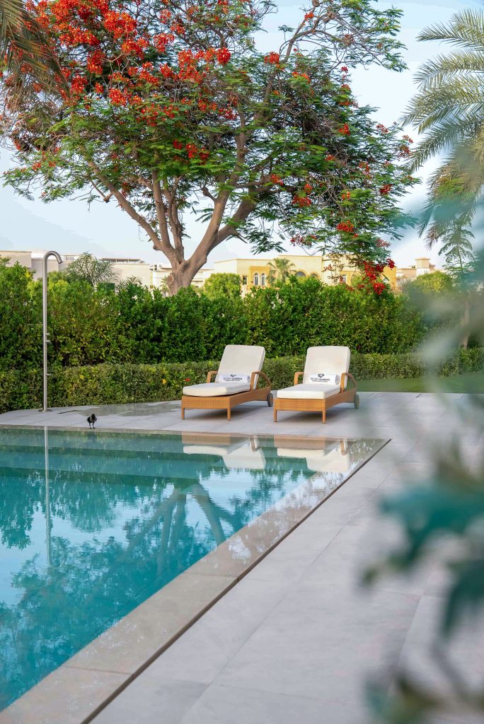 Villa landscape design and build in The Meadows, Dubai with a swimming pool, shaded poolside seating, built-in bench and garden lighting
