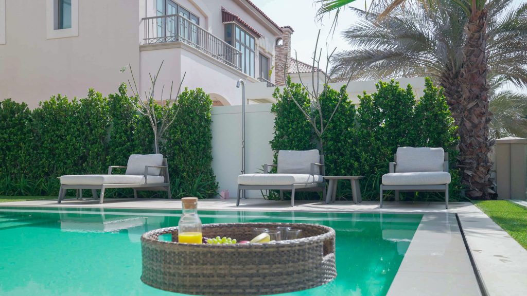 Villa landscape design and build in Jumeirah Golf Estates, Dubai with a swimming pool, poolside lounge seating, lawn and shaded pergola
