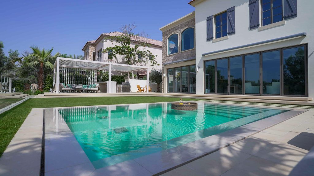 Villa landscape design and build in Jumeirah Golf Estates, Dubai with a swimming pool, poolside lounge seating, lawn and shaded pergola
